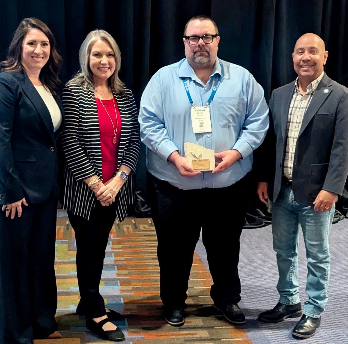 Four people smiling for a photo with the West U Parks & Rec's, Jeremy Veld, holding the TRAPS awa